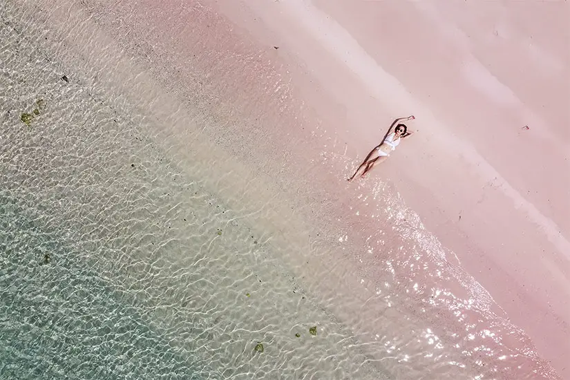 Woman Sunbathing on the Pink Sand Beach of the Bahamas